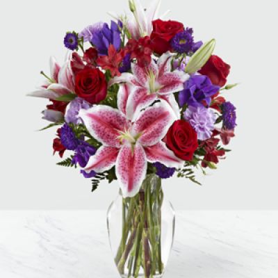 The Stunning Beauty Bouquet blooms with rich, bold blooms, making this a fresh flower bouquet that simply never goes out of style!

Fragrant Stargazer Lilies take center stage of this arrangement as they stretch their long star-shaped blooms across a bed of red roses, purple double lisianthus, lavender carnations, red Peruvian Lilies, purple matsumoto asters, and lush greens.